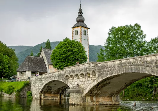 Stone bridge with a rustic bell tower in the background