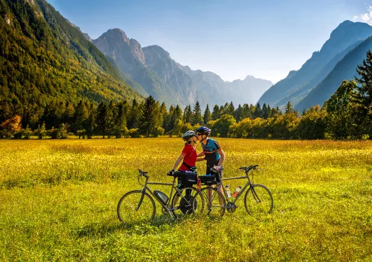 Two cyclists standing next to their bikes, kissing