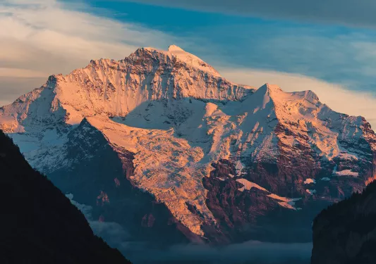 Large, snow-capped mountain with the sunset hitting on it