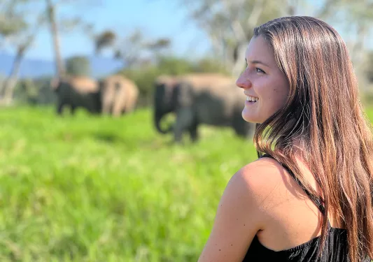 Woman smiling with tall elephants in the background