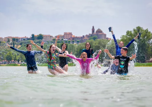 Group of kids in the ocean with their hands in the air