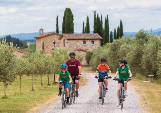 Family riding bikes on a gravel road with a brick church building in the background