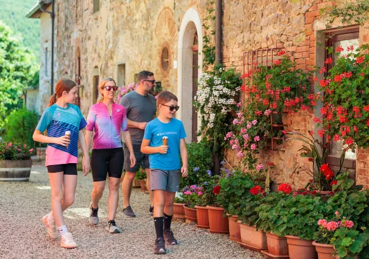 Family walking along a brick building with flowers in front, while all are holding ice cream cones