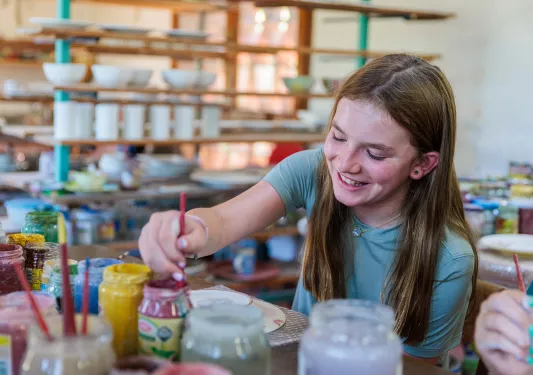 Girl smiling with dipping a paintbrush into paint