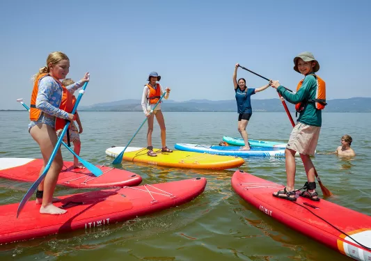 Group of people standing on top of kayaks in the middle of the ocean