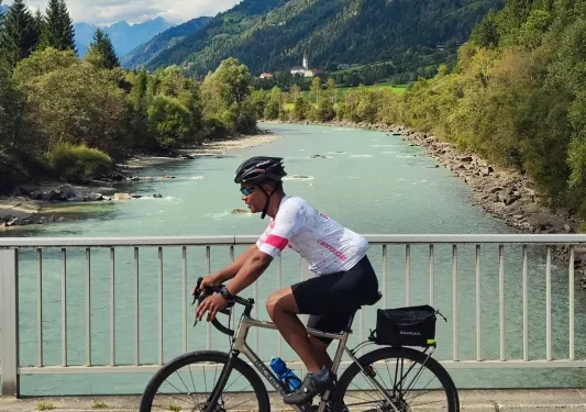 Man riding a bike on a bridge over a river