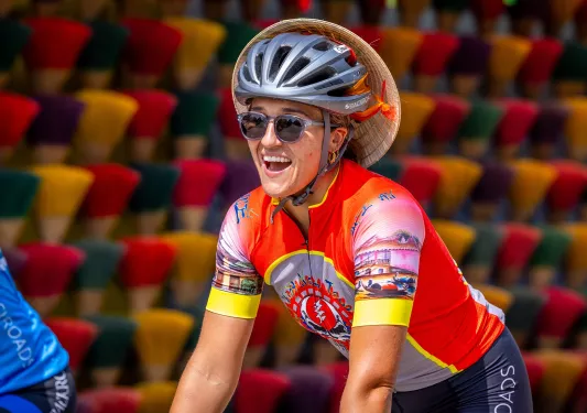 Woman smiling while riding a bike and wearing a helmet and sunglasses