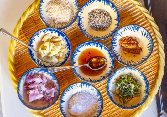 Straw tray full of different spices and cooking oils