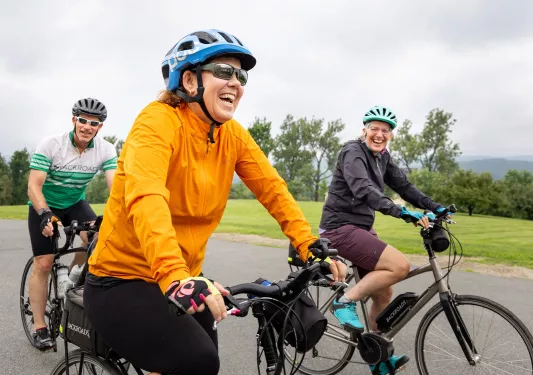 Group of people smiling while riding their bikes on an empty road