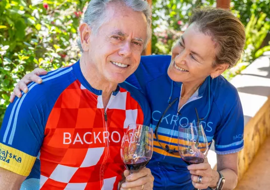 Man and woman holding wine glasses, smiling while looking at each other
