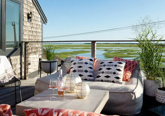 Outdoor balcony with cushioned sofas looking out towards a marsh