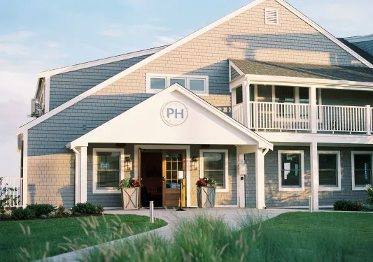 Exterior view of white and gray hotel building with a grass field in front