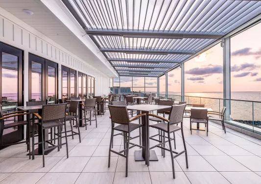 Outdoor balcony and patio with tall chairs and tables looking out to the ocean
