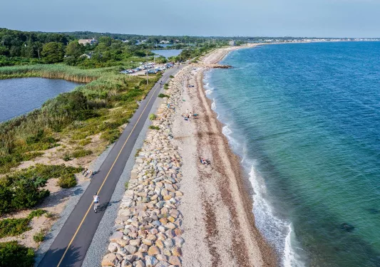 Person riding their bike on a road next to the beach