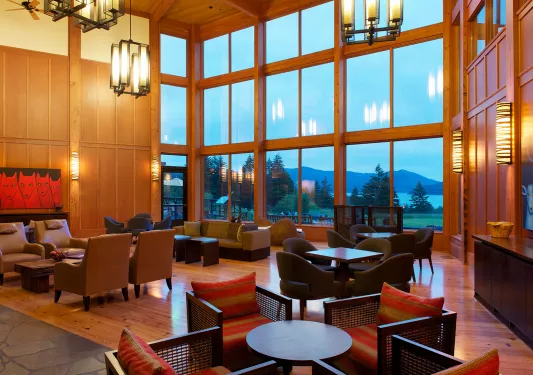 Lounge and seating area with cushioned chairs and tables, with a large glass wall