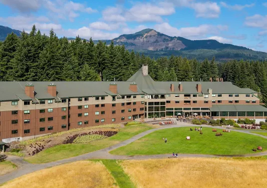 Exterior view of large brown hotel building, with a grass field in front