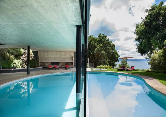 Outdoor pool with a large building covering and a lake in the background