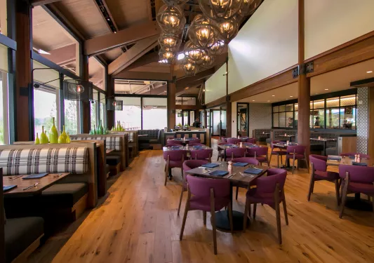 Restaurant dining area with cushioned booths and chairs around wooden tables