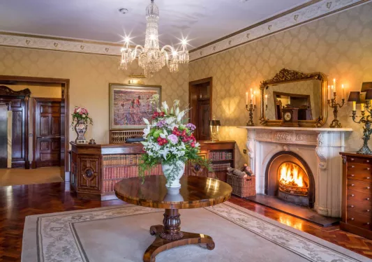 Hotel lobby with a stone fireplace and circular table, with a potted bouquet of flowers