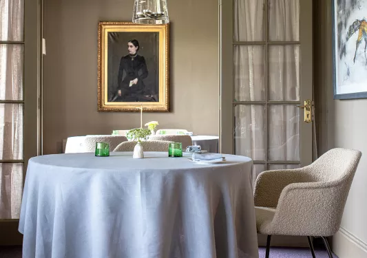 Circular dining table with gray cloth, and paintings on the wall