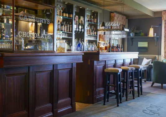 Indoor bar with redwood counters and cushioned stools, with alcohol bottles along the walls