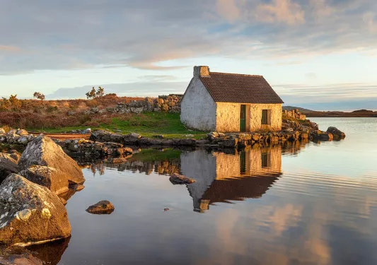 Stone house in front of a lake with boulders to the right