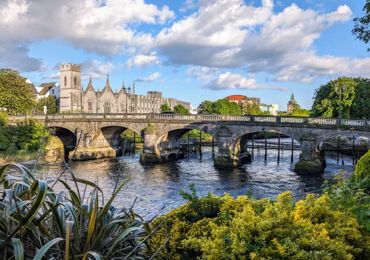 Stone bridge over a river leading to a castle-like building