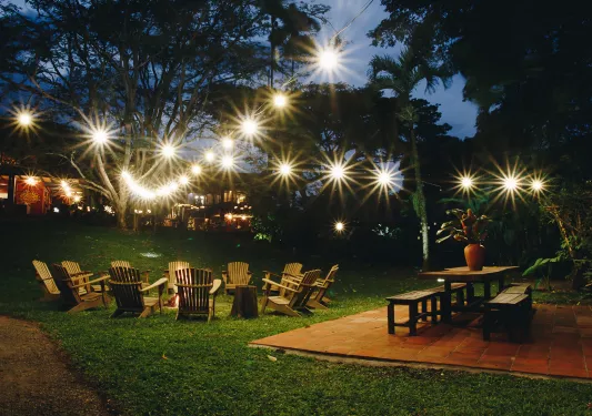Outdoor patio with with wooden chairs around an open fire pit