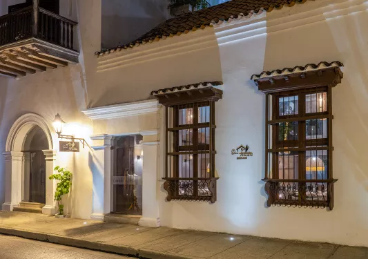 Exterior view of a white hotel building with brown accents and lights along the sidewalk