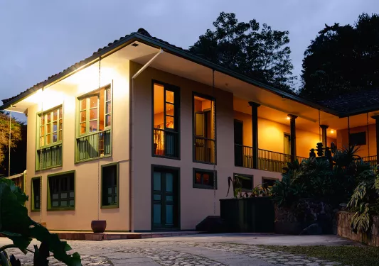 Exterior view of white building with green accents, and orange illuminated lights