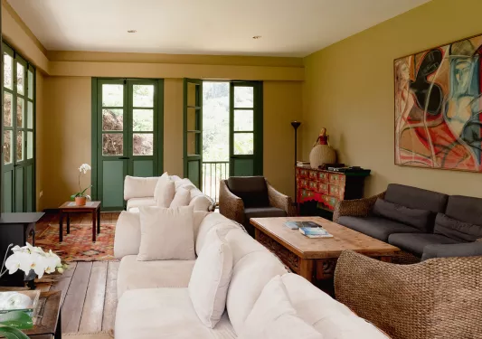 Room with cushioned white and gray couches, with green doors in the background