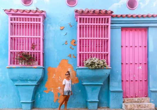 Woman standing in front of a blue building with pink windows