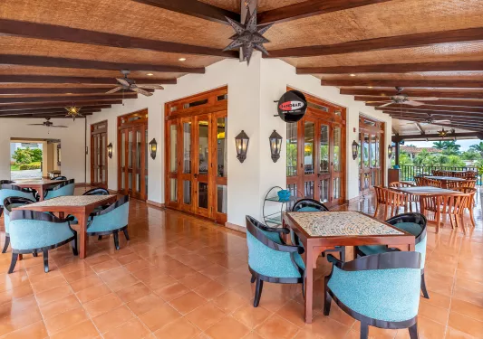 Outdoor patio with dining tables and cushioned, blue chairs