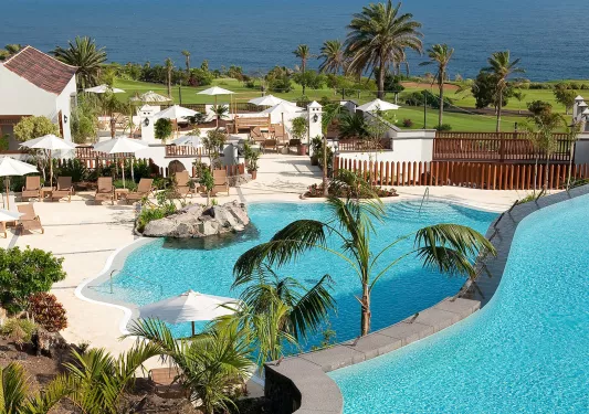 Outdoor, multilevel pool with an outdoor patio in the back, and the ocean in the distance