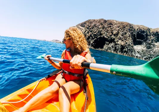 Woman paddling on an orange kayak