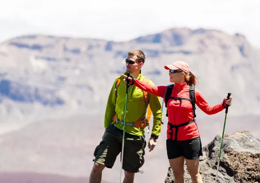 Man and woman with hiking poles, pointing and looking out to mountains