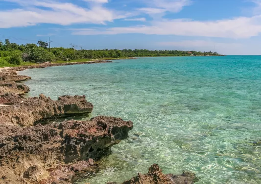 Beach shore with rocky cliffs and blue waters on the right