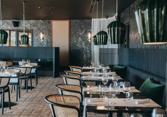 Indoor dining hall with woven chairs and green sofas