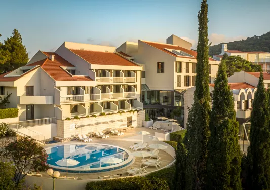 Exterior view of yellow and brown hotel building with a circular pool outside