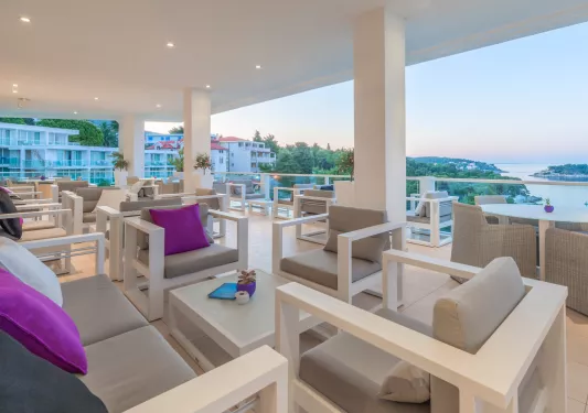 Outdoor patio with gray, cushioned chairs and a large river in the distance