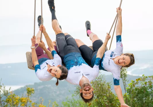 Man and two woman on a large swing, smiling