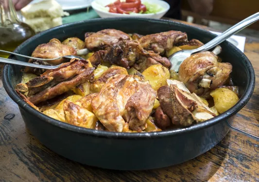 Cast-iron dish of cooked meat and potatoes