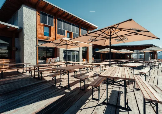 Outdoor patio with wooden tables and chairs under umbrellas