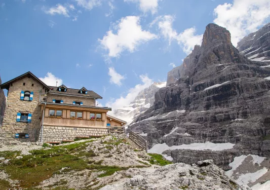 Large, stone building on top of a hill, with a large, snow-capped mountain to the right