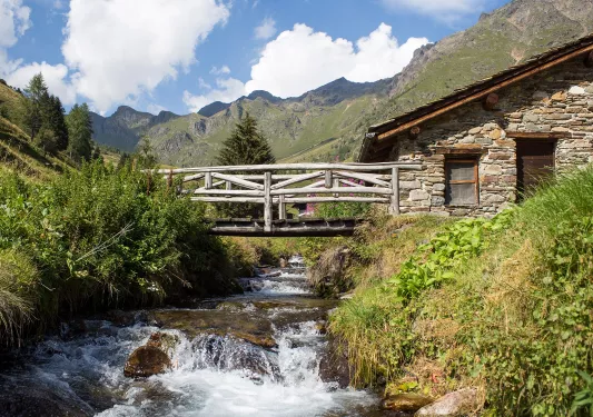 Small river under a wooden bridge attached to a stone building