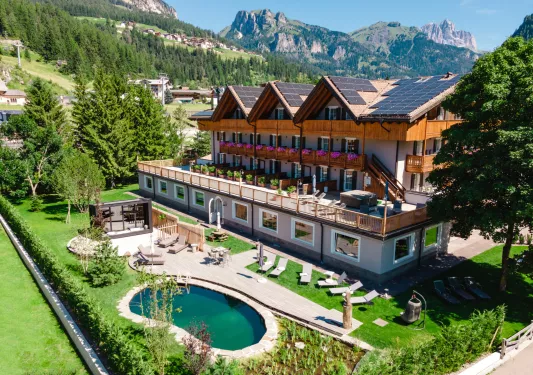 Exterior view of large hotel building with an outdoor patio and garden, and a small outdoor pool