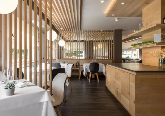 Restaurant dining hall with wooden counters and white tables with black and beige chairs
