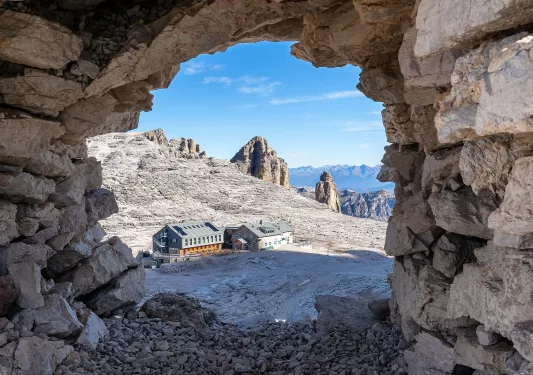 Large stone archway with a building in a gravel area
