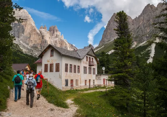 Group of people walking up a hill towards a white building