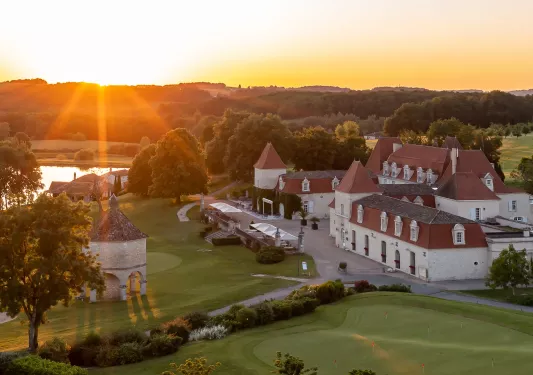 Sky, exterior view of white and red hotel complex, with large grass fields in front